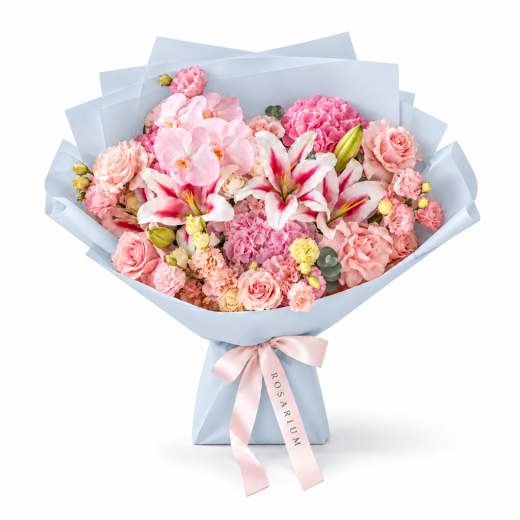 Blush Spectacle, pink orchids, pink and white lilies, blush roses, hydrangea and carnations in blue wrapping