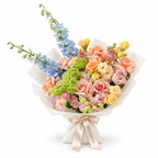 Spring with a Twist, blue delphinium, peach roses, yellow spray roses and blush carnations in off-white wrapping