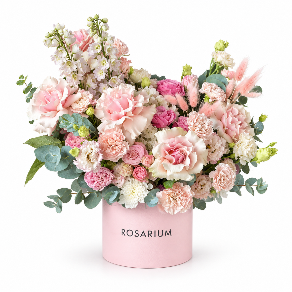 Blush Pirouette — Open blush roses, pink spray roses, carnations and lisianthus with pale stock, eucalyptus and soft decorative accents in a blush box
