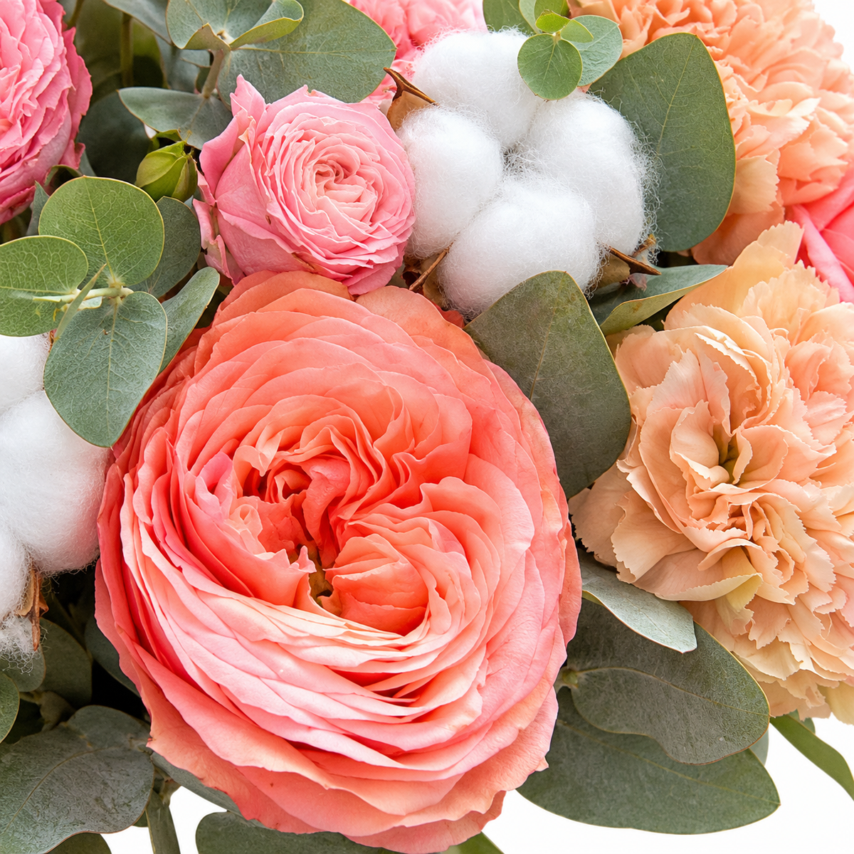 Peachy Magic: close-up of coral roses, peach carnations, cotton and eucalyptus