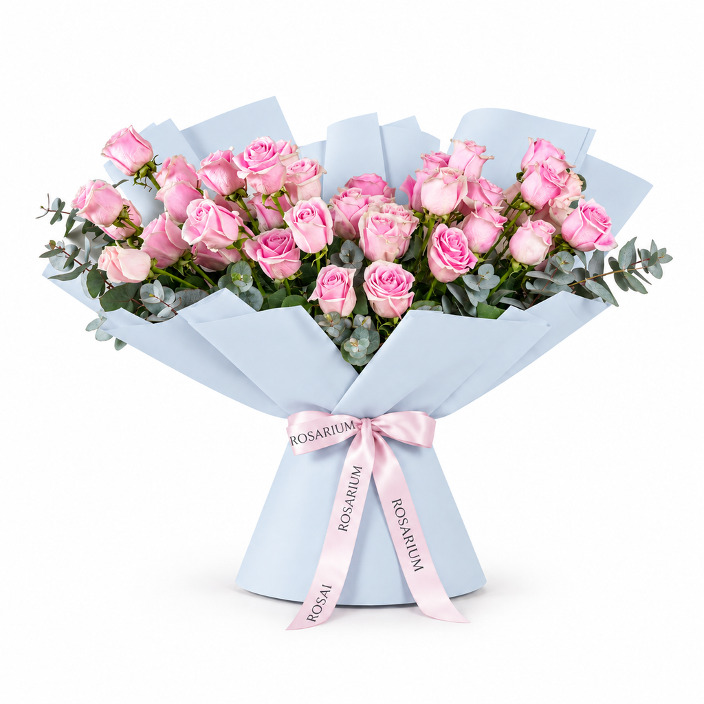 Wide bouquet of pink roses and eucalyptus in blue wrapping with a Rosarium ribbon