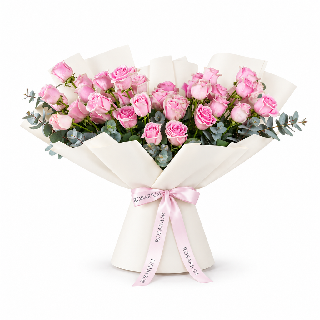 Wide bouquet of pink roses and eucalyptus in off-white wrapping with a Rosarium ribbon