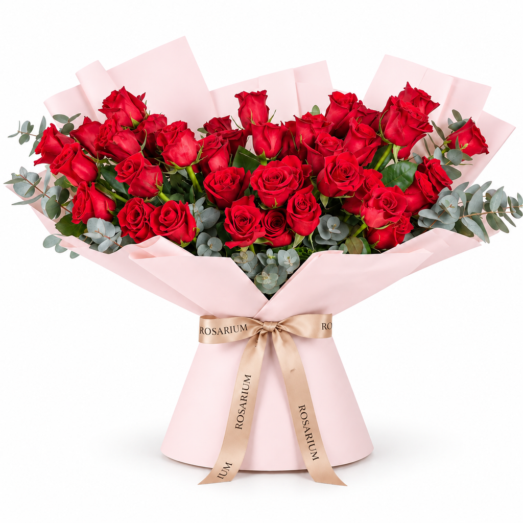Wide bouquet of red roses and eucalyptus in light pink wrapping with a Rosarium ribbon